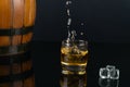 Glass of whiskey with splash, on a black background. old barrel. ice Royalty Free Stock Photo