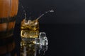 Glass of whiskey with splash, on a black background. old barrel. ice Royalty Free Stock Photo