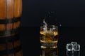 Glass of whiskey with splash, on a black background. old barrel. ice Royalty Free Stock Photo