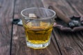 A glass of whiskey stands on a wooden table. Against the background of a cigar with an ashtray out of focus