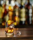 Glass of whiskey on wooden table top and blurred sparkling bar at the background Royalty Free Stock Photo