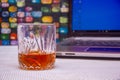 A GLASS OF WHISKEY AND LAPTOP SHOT ON A COLORFUL BACKGROUND Royalty Free Stock Photo