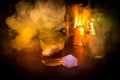 Glass of whisky on wooden bar closeup with bottles blurred view on dark background with light and smoke. Single glass of whisky on Royalty Free Stock Photo