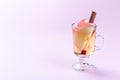 Glass of white glogg or mulled wine with apple slices and cinnamon stick on a pink background, horizontal, copy space Royalty Free Stock Photo