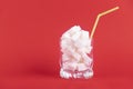 A glass of white glass with a straw filled with white cubes of refined sugar on a red background. Copy space Royalty Free Stock Photo