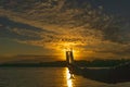 A glass of white wine against the backdrop of a beautiful sunset, the sun and sky are reflected in an alcoholic drink. The concept