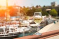 Glass of white wine against the backdrop of the Mediterranean sea and the port with yachts in a tourist town in the Royalty Free Stock Photo