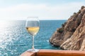 A glass of white wine. Wine against the backdrop of the sea coast and a sunny summer beach. Wine tasting and relaxation at the