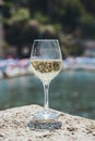 Glass of white wine against the background of the Mediterranean beach and the sea in a tourist town in the summer under Royalty Free Stock Photo