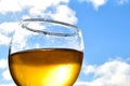 Glass of white wine against a blue sky with white clouds on a sunny day Royalty Free Stock Photo