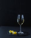 A glass of white wine on a black table with a fruit dessert Royalty Free Stock Photo