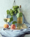 Glass with white wine, a bunch of grapes, peaches on a gray background, on the table