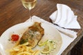 Glass of white wine with fried hake fish and chips