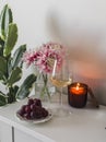 A glass of white wine, red grapes, a lit candle on the table in a cozy home living room Royalty Free Stock Photo