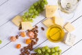 Glass of white wine with snacks - various types of cheese, figs, nuts, honey, grapes on a wooden boards background Royalty Free Stock Photo