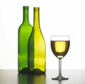 Glass of white wine with two green bottles Royalty Free Stock Photo
