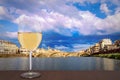 Glass of white wine with view of bridge in Florence during sunset - Ponte alla Carraia, five-arched bridge over Arno River in the