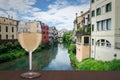 Glass of white wine with view of traditional canal street with bright colorful buildings, green bushes and blue sky in Padova, Royalty Free Stock Photo