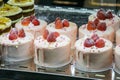 Glass window in a bakery shop with different types of cakes in a showcase. Delicious creamy fruit cakes decorated with fresh Royalty Free Stock Photo