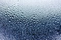 Glass window in raindrops, beautiful blue gradient color with water drops, misted mirror surface texture background close up Royalty Free Stock Photo