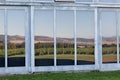 Glass windows and doors on the exterior of a building reflecting the view of a vineyard
