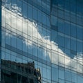 Glass windows of a modern building reflect the sky and clouds, creating a dynamic Royalty Free Stock Photo