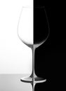 Glass of wine on a black and white background, with reflection. Domino concept Royalty Free Stock Photo