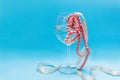 In a glass of wine on a blue background are beads of pink pearls Royalty Free Stock Photo