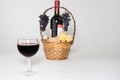 A glass of wine. A bottle of red wine, grapes and picnic basket with cheese slices on white background. Royalty Free Stock Photo