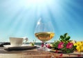 glass of  wine  ,cup of coffee  on wooden bench   wild rose hip  meadow flowers  and at sea , summer beach blue sky flying petal Royalty Free Stock Photo