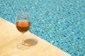 Glass wine glass on the edge of a swimming pool. Rose wine in a glass goblet. Money abundance concept Royalty Free Stock Photo