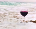 Glass of wine in the foam of the sea on the shore Royalty Free Stock Photo