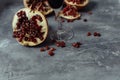 A glass of wine on a gray background among pomegranates. Close pomegranate and red pomegranate seeds