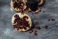 A glass of wine on a gray background among pomegranates. Close pomegranate and red pomegranate seeds