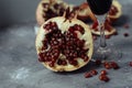 A glass of wine on a gray background among pomegranates. Close pomegranate and red pomegranate seeds