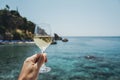 Glass of wine in hand. A glass of red wine against the background of the Mediterranean beach and the sea in a tourist Royalty Free Stock Photo