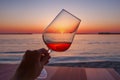 A glass of wine in the hand of a woman against the background of the sea. Beautiful sunset by the sea. The sun in a glass of wine Royalty Free Stock Photo