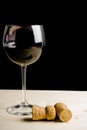 Glass of wine near two cork on old wood Royalty Free Stock Photo