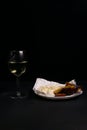 glass of wine next to a slice of cheese, plums on a black background Royalty Free Stock Photo