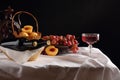 Glass of wine, peaches and grapes on dark background