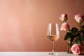glass of wine with pink roses flowers in vase and bottle on peach background with copy space, romantic template design Royalty Free Stock Photo