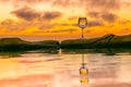 Glass of Wine on rock with reflection in water pond. beautiful clouds of sunset in background Royalty Free Stock Photo