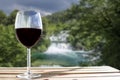 Glass of wine on wooden table with big waterfall blur background in Croatia