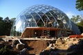 A glass and wood dome house under construction, with scaffolding and workers visible. Generative AI Royalty Free Stock Photo