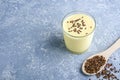 Glass of yellow mango or banana yogurt or smoothie with flax seeds on gray background. Turmeric Lassie lassi. Healthy dairy