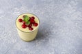 Glass of yellow mango or banana yogurt or smoothie on gray background. Turmeric Lassie lassi served with berries. Healthy dairy