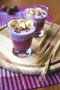 A glass of yogurt with blueberries, cereals, banana and walnuts