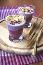 A glass of yogurt with blueberries, cereals, banana and walnuts