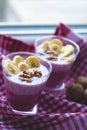 A glass of yogurt with blueberries, cereals, banana and walnuts