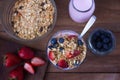 Glass with yogurt, cereals, strawberries and blueberries on wooden table - top